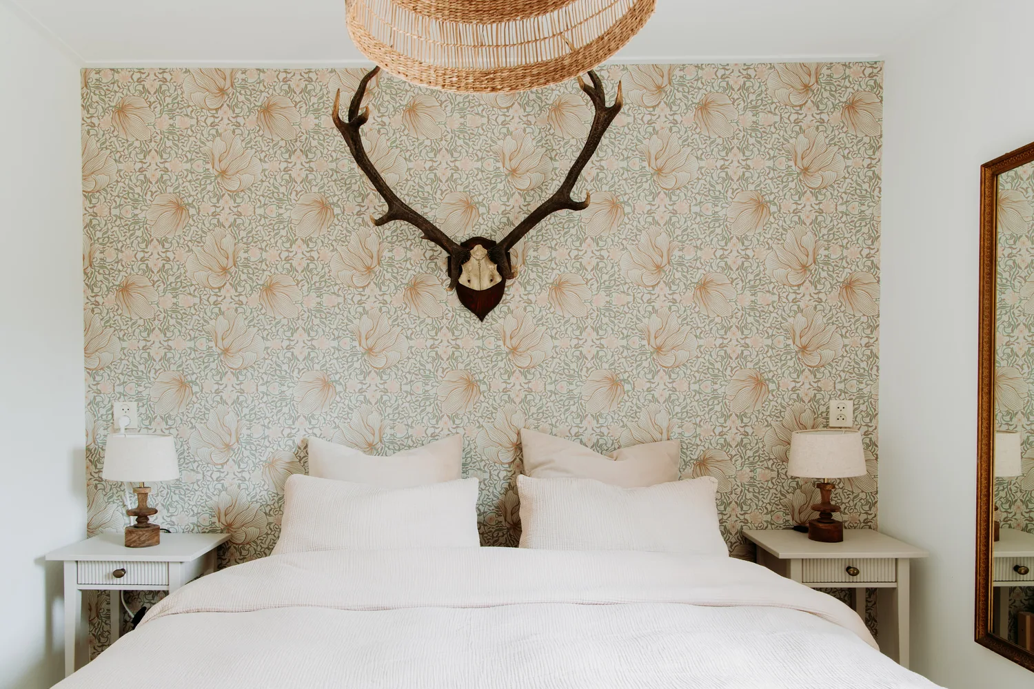 Slaapkamer met tweepersoonsbed en gewei aan de muur