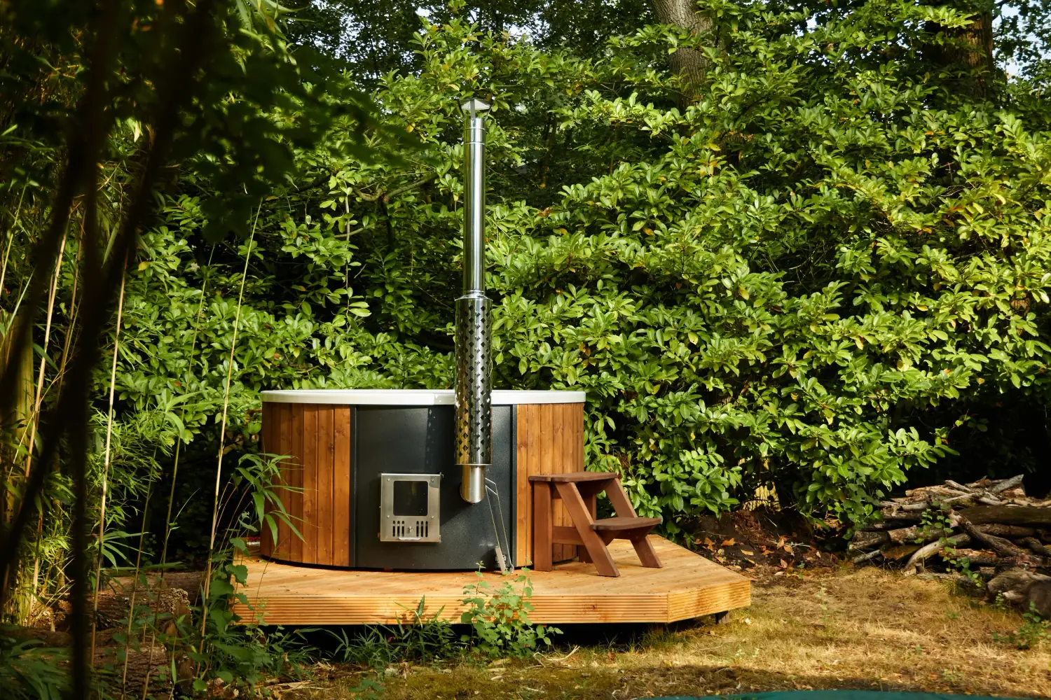 De houtgestookte hottub op een houten vlonder tussen het groen