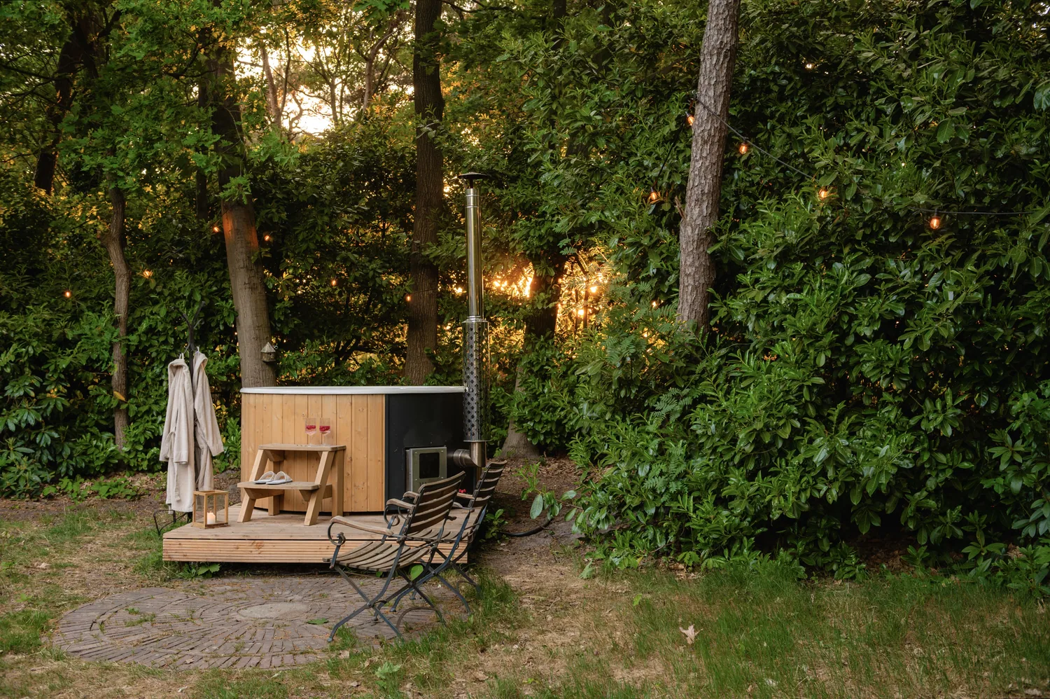Houtgestookte hottub in de bostuin van Boshutjemutje, met priklichtjes in de bomen