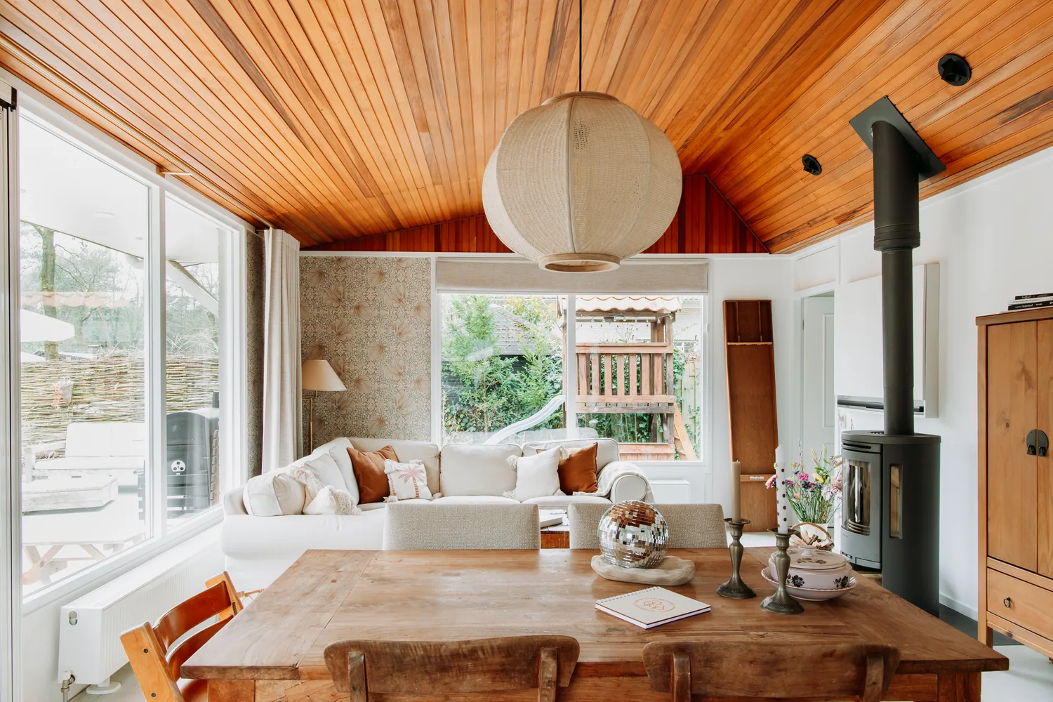 Lichte woonkamer met houten plafond, eettafel en bank